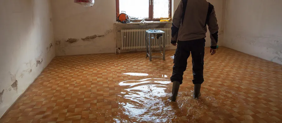 man with rubber boots standing in flooded basement 