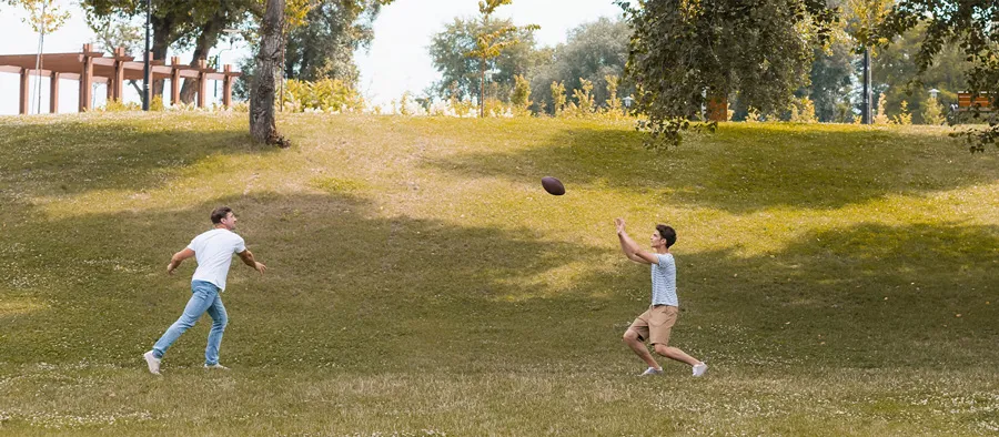 son and father throwing a football in a park